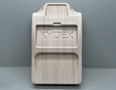 A light-colored, rectangular object with rounded edges and an embossed "KYPEX" logo. It has a grooved design and a raised section at the top. The background is plain gray.